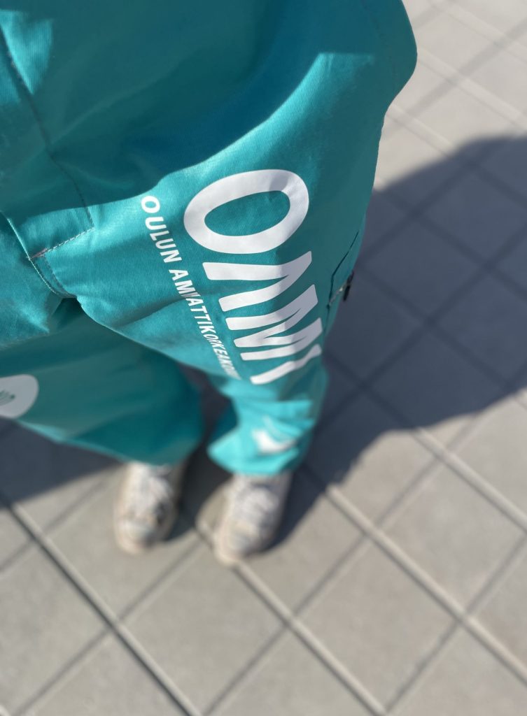 Kuva henkilön jaloista päällään OUTO RY:n turkoosit haalarit