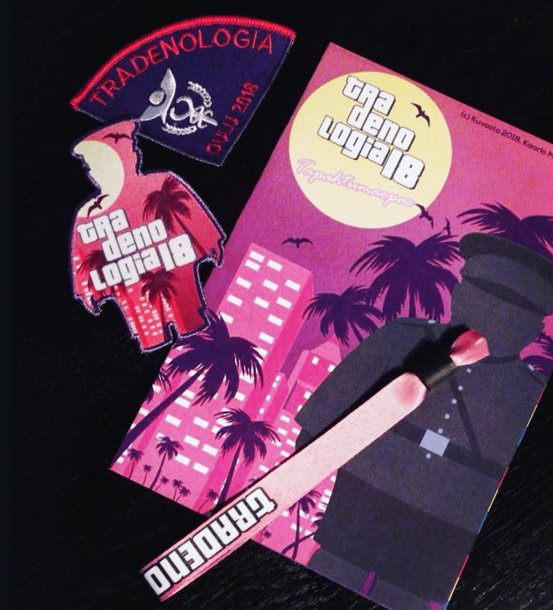 Tradenologian tapahtumaopas, ranneke ja kaksi haalarimerkkiä.